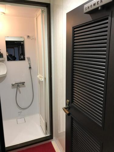 a bathroom with a shower and a black door at Guest House Kuranomachi ゲストハウス蔵の街 in Tochigi