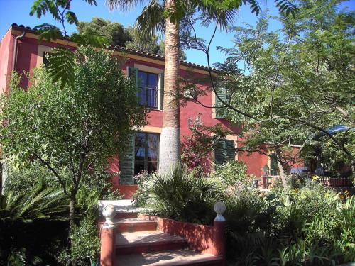 a red house with a palm tree in front of it at Sous L'Olivier in Menton