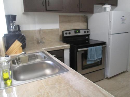 a kitchen with a sink and a stove and a refrigerator at Pedro's Place in Tamuning