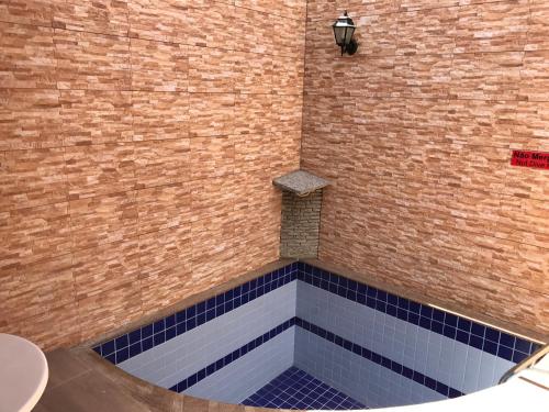 ducha con azulejos azules y pared de ladrillo en Cassino Motel en Natal