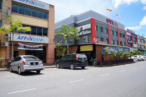 two cars parked in a parking lot in front of a building at Greens Hotel & Suites in Bintulu