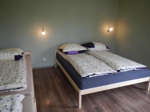 two beds in a bedroom with two lights on the wall at Kempings "Ceļmalnieki" in Liepāja
