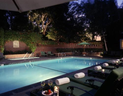 a swimming pool with a table and chairs and an umbrella at The Stanford Park Hotel in Menlo Park