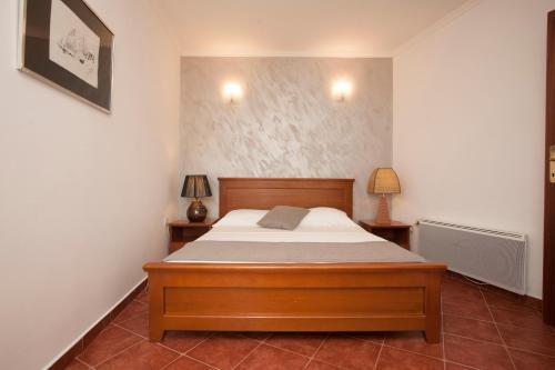 a bedroom with a wooden bed and two lamps at Guest House Medin in Petrovac na Moru