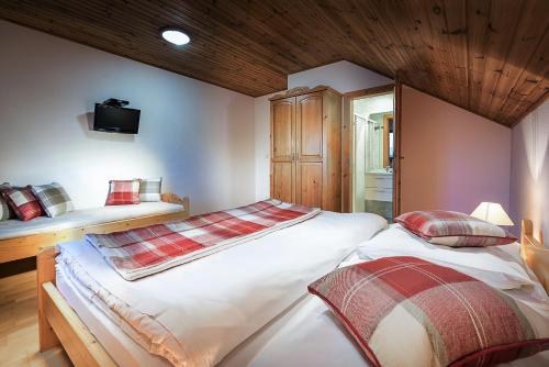 a bedroom with two beds and a tv on the wall at Chata Adamec in Ždiar