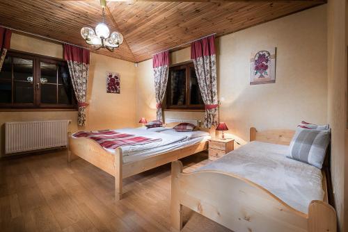 a bedroom with two twin beds and a wooden ceiling at Chata Adamec in Ždiar