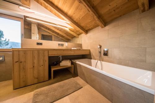 La salle de bains est pourvue d'une baignoire et d'un lavabo. dans l'établissement hubertus dolomites, à Fiè