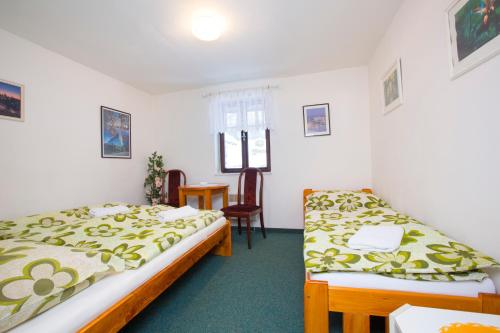 a room with two beds and a table and a chair at Chata Pod lipami in Rokytnice nad Jizerou