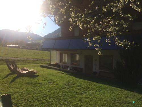 a house in a field with a bench in the grass at Ferienwohnungen Marchanger in Niederau