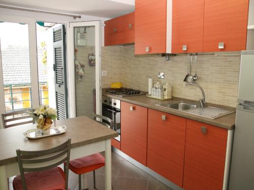 uma cozinha com armários vermelhos e uma mesa com cadeiras em Colombo Flexyrent Studio em Rapallo