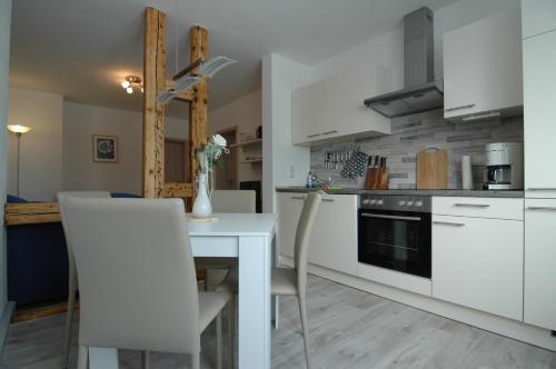 uma cozinha com armários brancos e uma mesa e cadeiras em Extrablatt em Oberhof