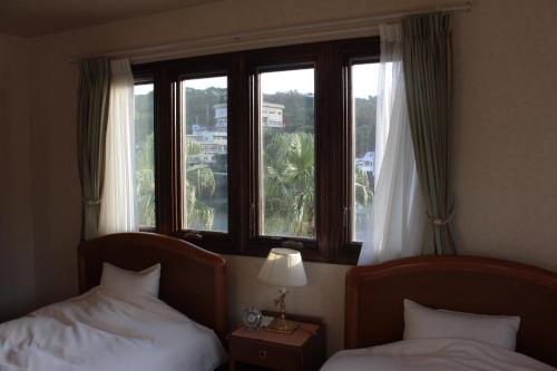 two beds in a hotel room with a window at La Isla Tasse in Yakushima