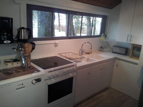 une cuisine avec un évier, une cuisinière et une fenêtre dans l'établissement La Palombière, plage à 150m, à Meschers-sur-Gironde