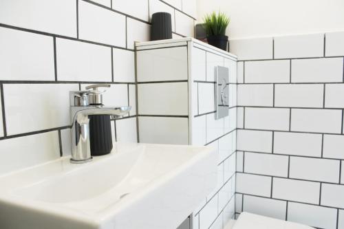 a bathroom with a sink and white tiled walls at Studio apartman in Zagreb