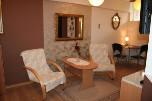 salon z 2 krzesłami, stołem i lustrem w obiekcie Apartament Manhattan w Olsztynie w Olsztynie