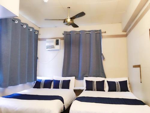 2 camas en una habitación con cortinas azules en Osaka Hostel en Hong Kong