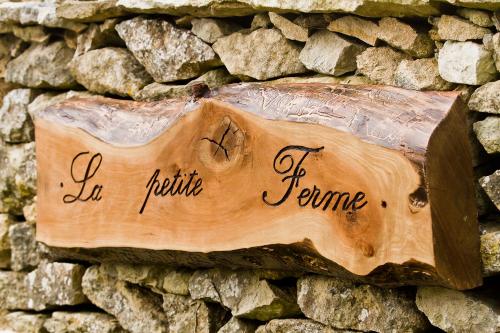 ein Holzschild an der Seite einer Steinmauer in der Unterkunft La petite Ferme in Chérence