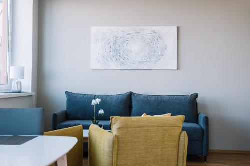 a living room with a blue couch and two chairs at Hestia Apartments Seaport in Tallinn