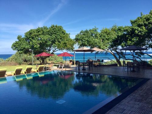 einen Pool mit Stühlen und Sonnenschirmen sowie das Meer in der Unterkunft Sooriya Resort & Spa in Tangalle