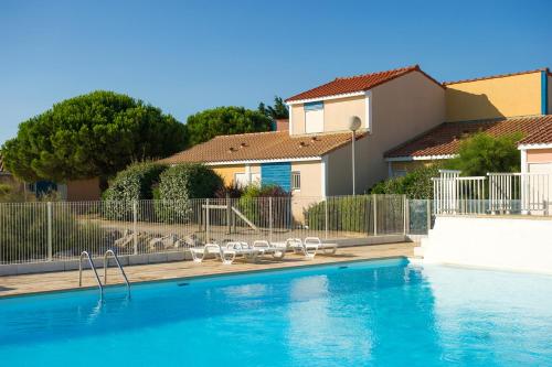 une piscine avec des chaises et une maison dans l'établissement Goélia Le Village Club Marin, à Port-la-Nouvelle