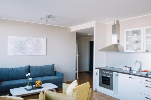 a kitchen and a living room with a blue couch at Hestia Apartments Seaport in Tallinn
