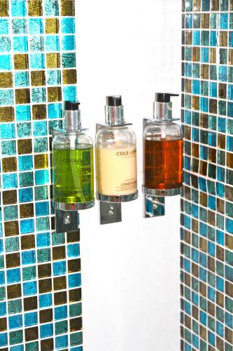three bottles ofodorizers sitting on a wall in a bathroom at Crompton Guest House in Hounslow