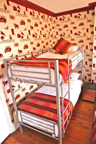 two bunk beds in a room with a wall with aiger at Crompton Guest House in Hounslow