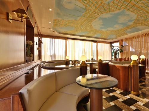 a waiting room with tables and a ceiling at Hotel Bristol in Sottomarina