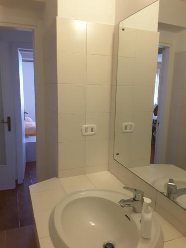 ein weißes Badezimmer mit Waschbecken und Spiegel in der Unterkunft Appartamento Poggio Romantico in Marciana