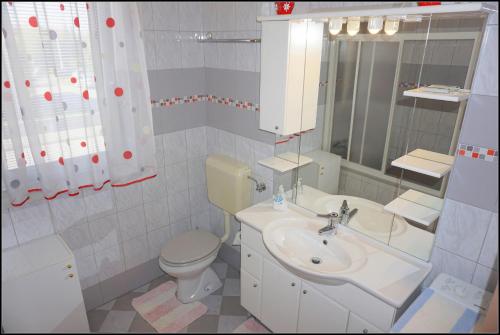 a bathroom with a sink and a toilet and a mirror at Orlando's Apartments OJ in Izola