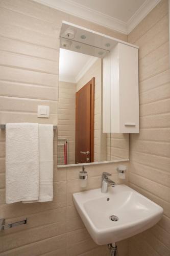 a bathroom with a sink and a mirror and towels at Guest House Medin in Petrovac na Moru