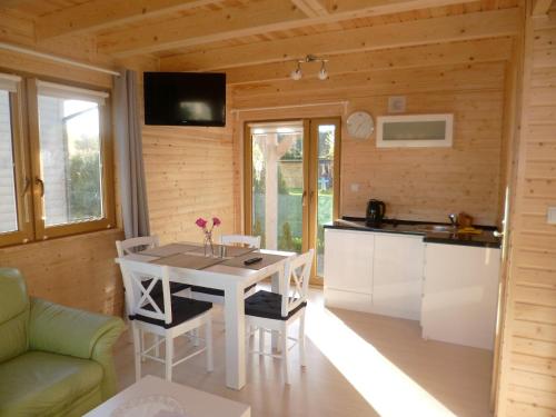 a kitchen and dining room of a log cabin with a table and chairs at Cztery Pory Roku in Trzęsacz