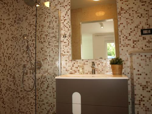 uma casa de banho com um lavatório e um chuveiro com um espelho. em Villetta Mia em Njivice