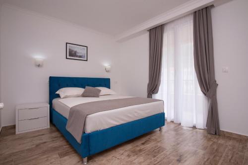 a bedroom with a blue bed and a window at Guest House Medin in Petrovac na Moru