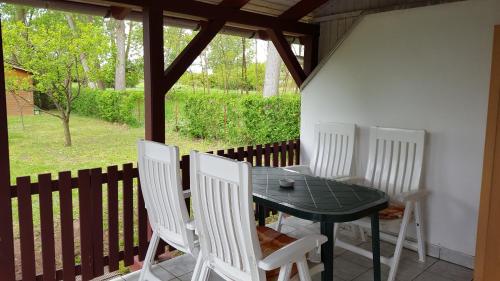una mesa y cuatro sillas blancas en un porche en Fácánkert Apartmanház, en Tiszafüred