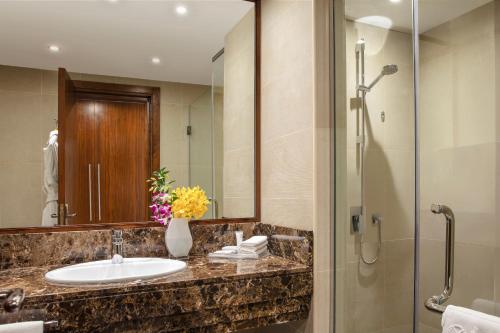a bathroom with a sink and a shower with a mirror at Jumeira Rotana – Dubai in Dubai