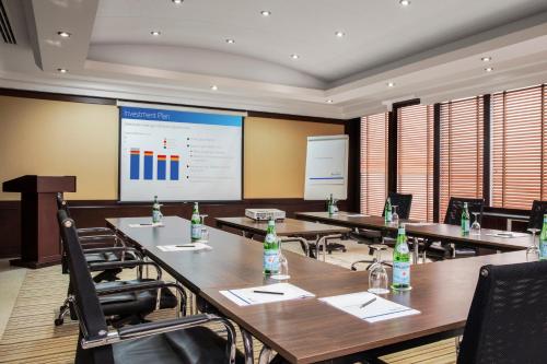 a conference room with tables and chairs and a projection screen at Jumeira Rotana – Dubai in Dubai