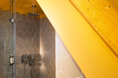 a bathroom with a shower with a yellow ceiling at Hotel Le Colombier Suites in Colmar