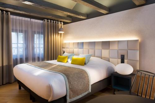 a hotel room with a bed and two lamps at Hotel Le Colombier Suites in Colmar