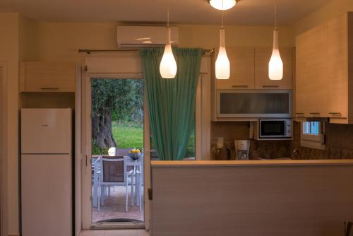 a kitchen with green curtains and a kitchen with a table at Olive Garden Villas and Apartments in Chrysi Ammoudia
