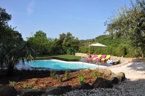 uma piscina com duas cadeiras e um guarda-sol em Les Bons Vivants Cévenols em Générargues