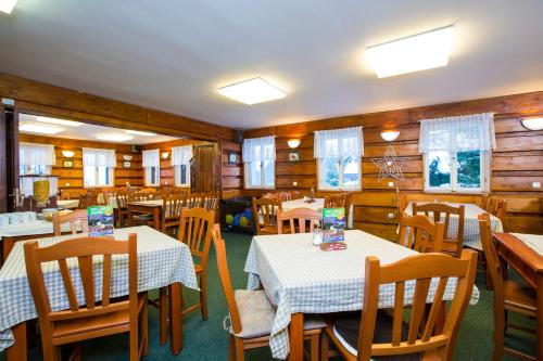 a dining room with tables and chairs and wooden walls at Chata Pod lipami in Rokytnice nad Jizerou