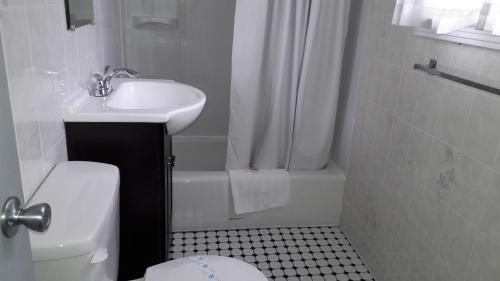 a white bathroom with a sink and a toilet at Pinebrook Motel in Lake George