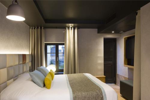 a bedroom with a large bed and a television at Hotel Le Colombier Suites in Colmar