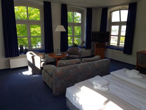 a living room with a couch and chairs and windows at Hotel Havenhaus in Bremen-Vegesack