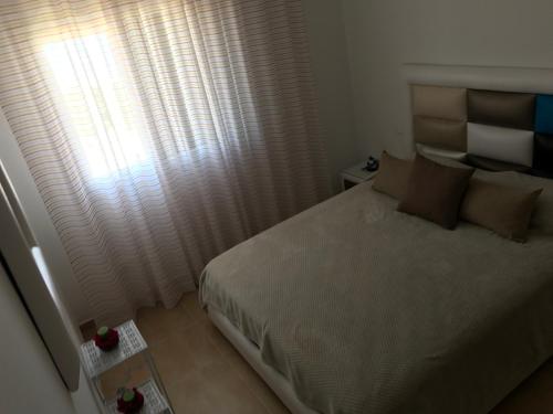 a bedroom with a bed and a window with curtains at Appartement Bellavista - Cabo Negro in Cabo Negro