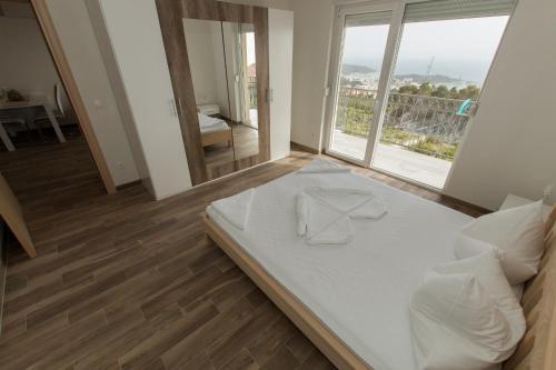 a bedroom with a white bed with a large window at Apartments Matanovi Dvori in Makarska