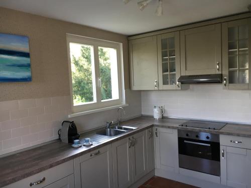 uma cozinha com armários brancos, um lavatório e uma janela em Holiday Home Castle View em Pierrefonds