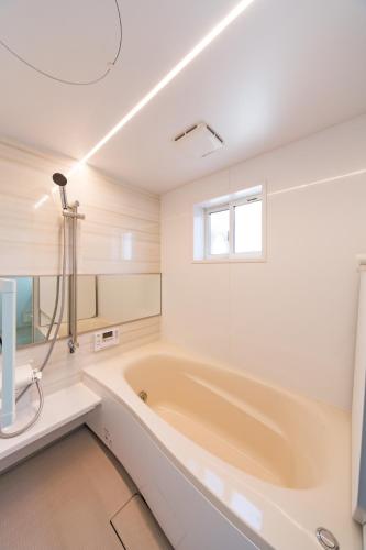 a white bathroom with a tub and a window at Kanazawa Seiren Le Lotus Bleu in Kanazawa