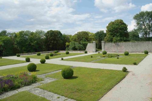 a garden with bushes and trees and a wall at Château de Montramé in Soisy-Bouy